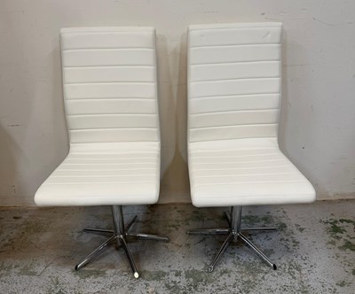 Lot 69 - A pair of white faux leather dining chairs on...