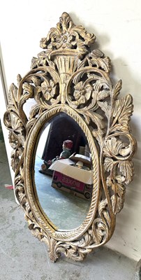 Lot 62 - An oval wall mirror featuring an ornate gilt...