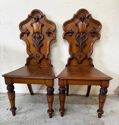 Lot 198 - A pair of Victorian oak hall chairs features...