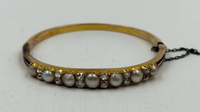 Lot 572 - A hinged gold braclet with a row of seven...